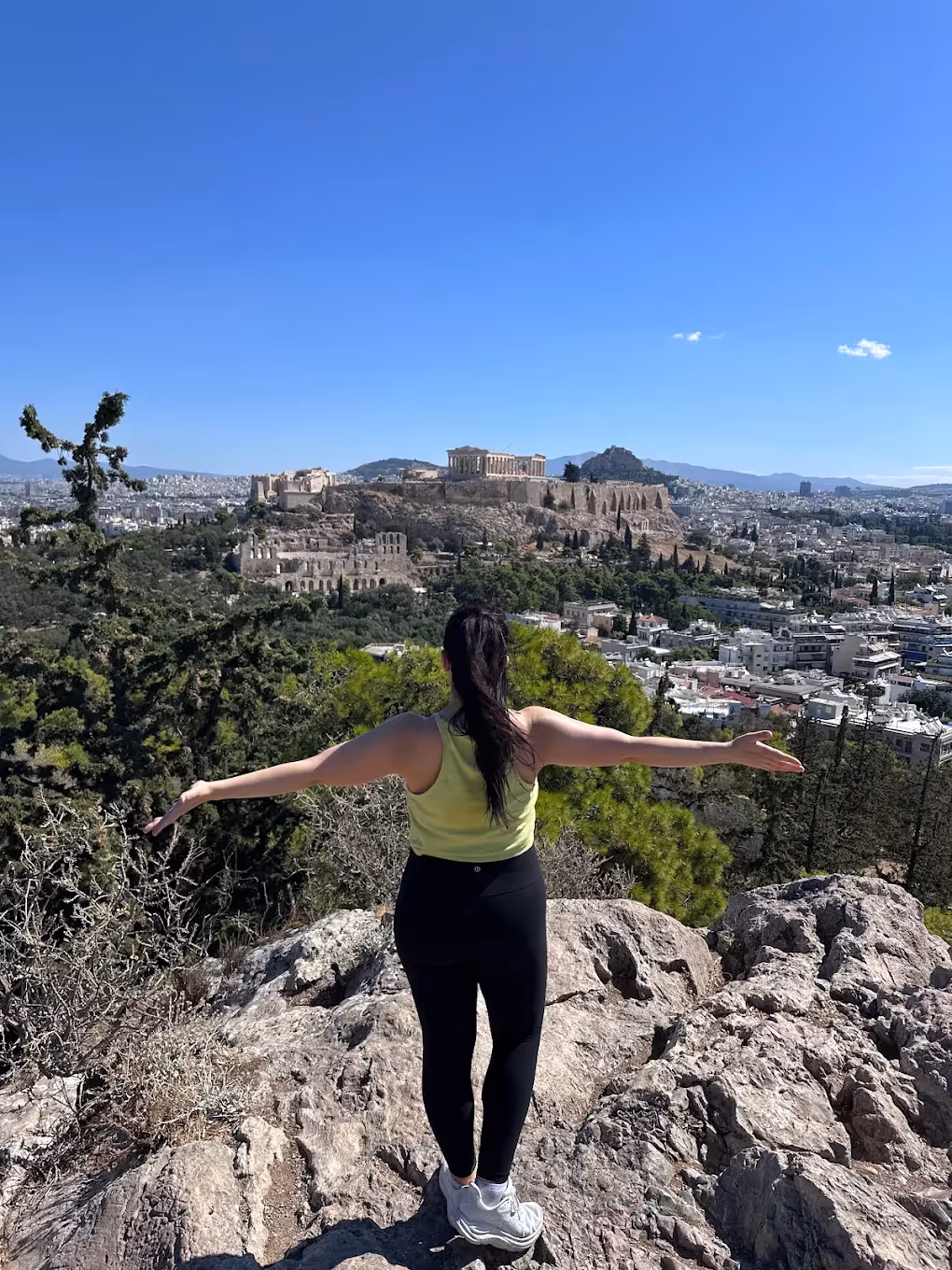 Walker on the rocks of Philopappos Hill with the Parthenon and the Acropolis directly behind